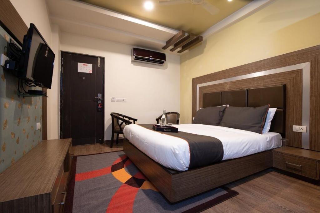 a bedroom with a large bed and a television at Hotel O Civil Lines Formerly City Palace in Jhānsi