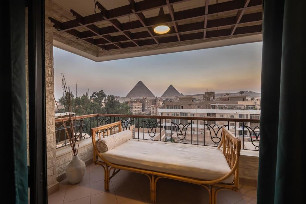 a balcony with a bench and a view of pyramids at Cozy vintage duplex Khan -khan luxe residence pyramids view in Cairo