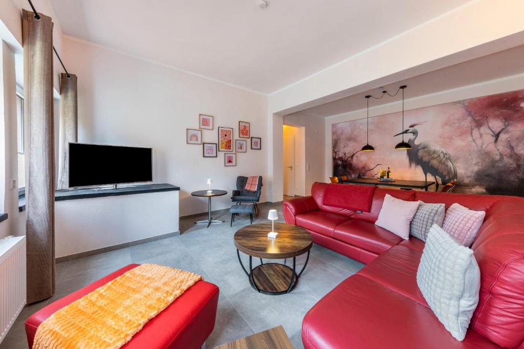a living room with a red couch and a table at Suiten im Alten Berghotel Johanna in Niedersalwey