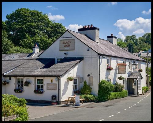 a white building with a sign that reads guest house at The Black Lion in Llanfair Talhaiarn