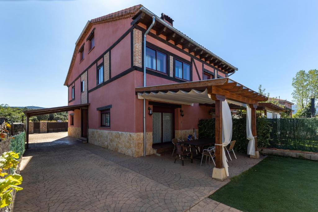 a pink house with a table and an umbrella at Casa Rural Arbana in Segovia