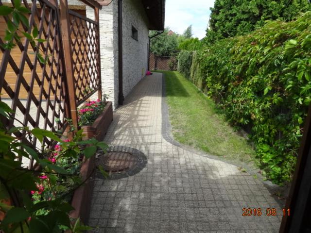 einen Ziegelweg mit einem Zaun und Blumen in der Unterkunft Studio Gdańsk in Danzig