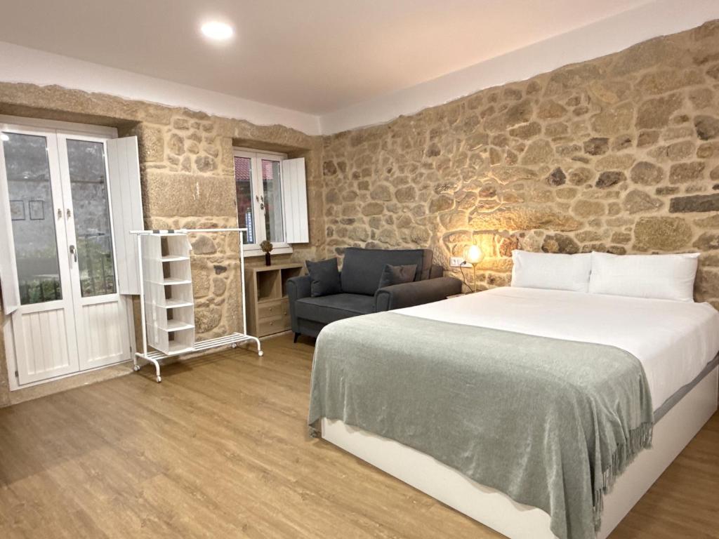 a bedroom with a bed and a stone wall at Padrón Plaza Lotf L2 by URent in Padrón