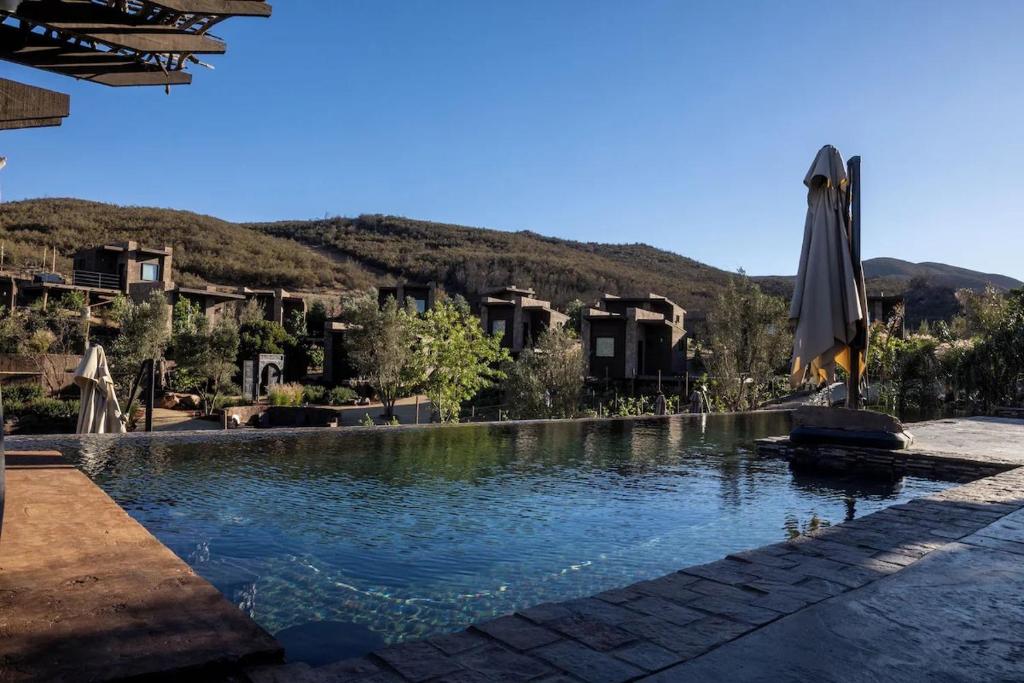a swimming pool with an umbrella and a resort at o2 Resort Valle de Guadalupe in Valle de Guadalupe