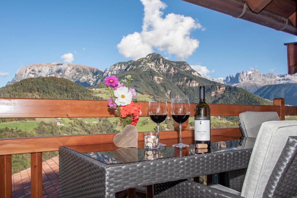 a table with wine glasses and flowers on a balcony at Wohnung Schlern Heigler Hof in Collepietra