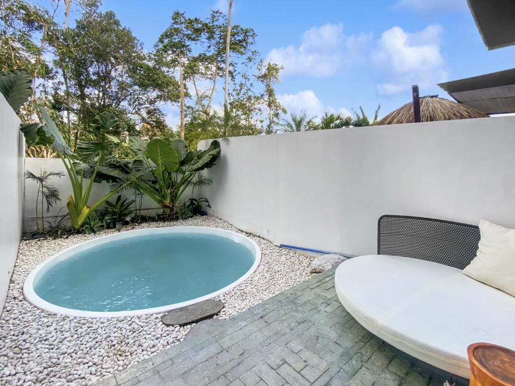 a hot tub on a patio with a couch and a surfboard at Villa Byu By Local Property Team in Balian
