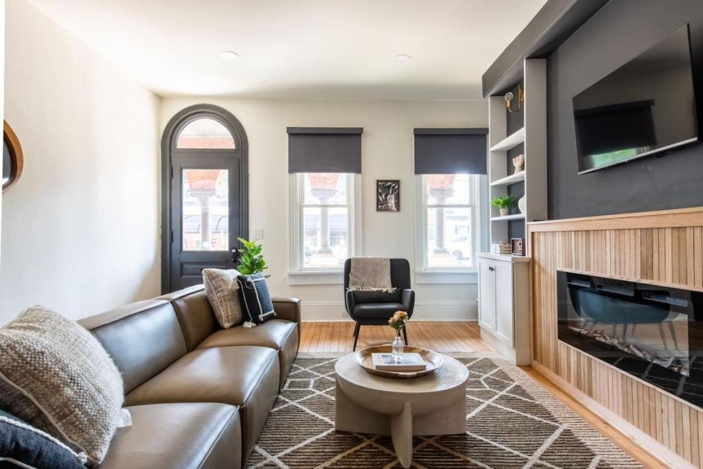 a living room with a leather couch and a tv at The Lancastrian House Downtown in Lancaster