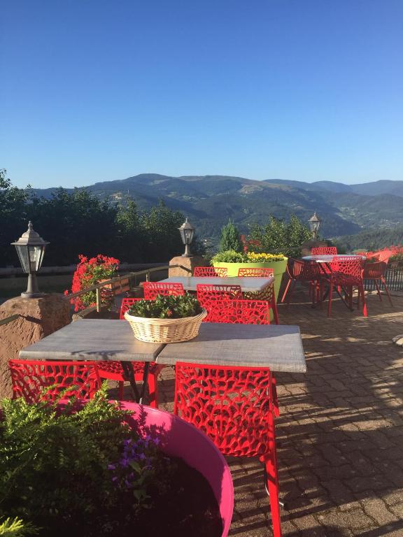 a table with red chairs and flowers on a patio at Hôtel Panorama in Munster