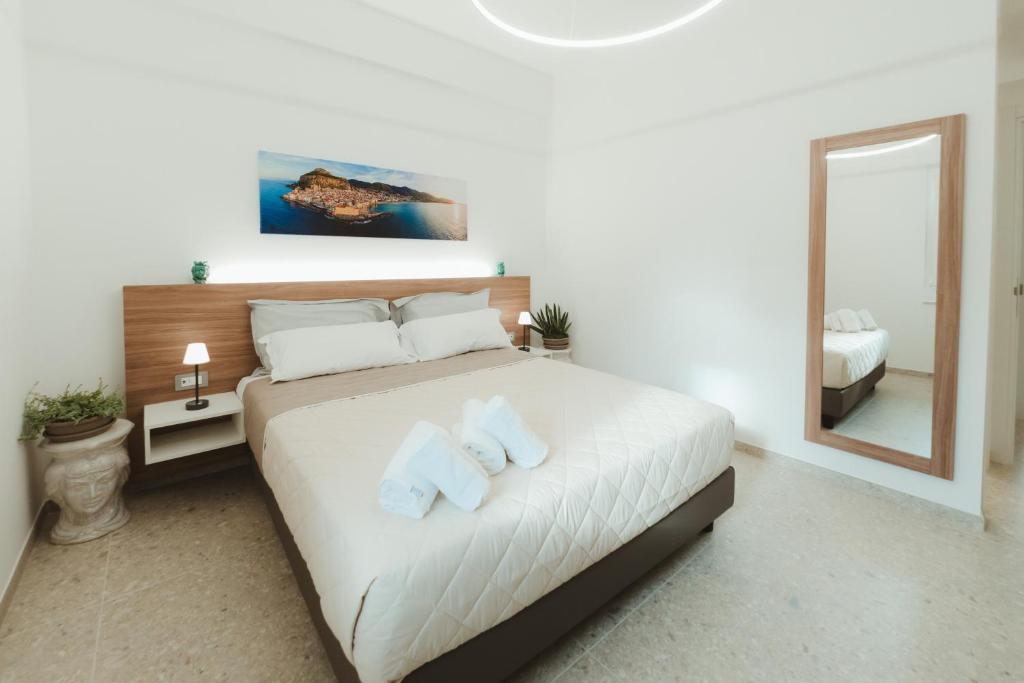 a bedroom with a bed with two pillows and a mirror at Verga 16 Deluxe Cefalù Apartments in Cefalù