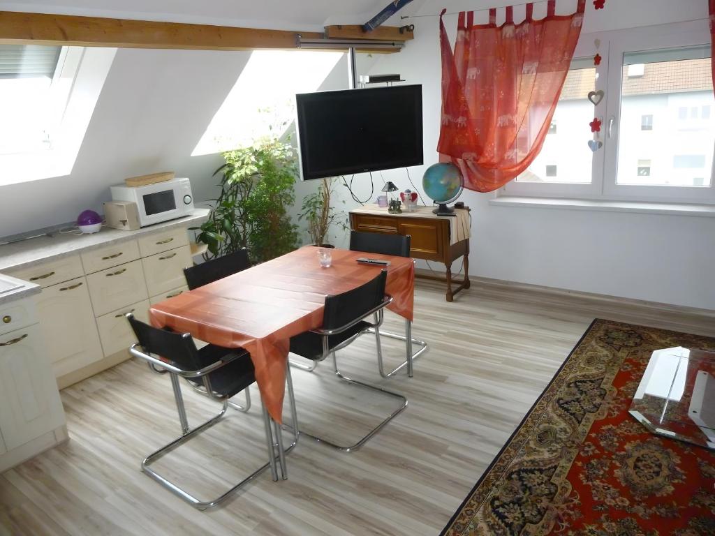 a kitchen with a wooden table with chairs and a tv at A Casa Alfred Kemmern in Kemmern