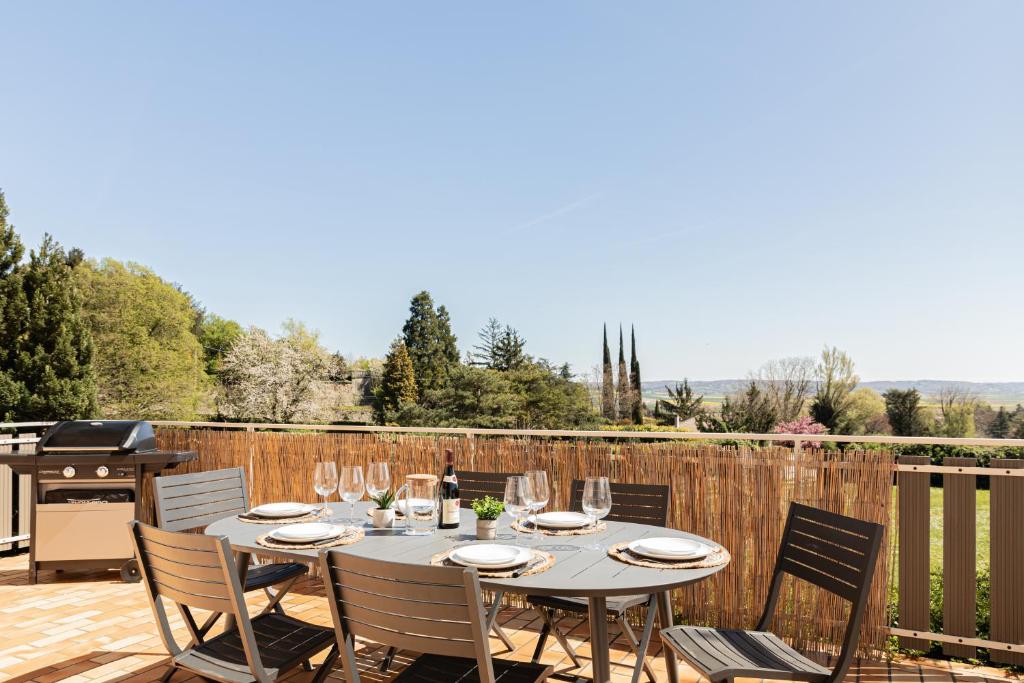 a patio with a table and chairs and a grill at Le Cocon des Allamandières in Chonas-lʼAmballan