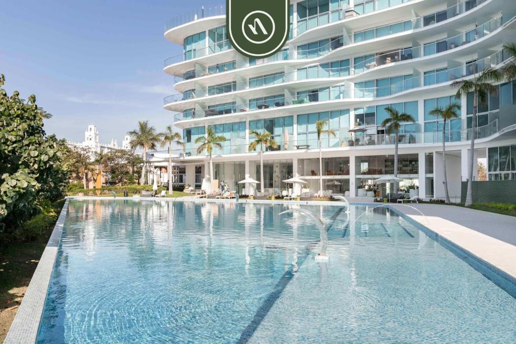 a swimming pool in front of a large building at New 2BR APT - Beach Access - Pool - GYM - Jacuzzi in Nuevo Vallarta