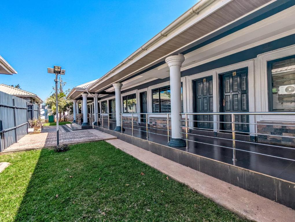un edificio con un portico con colonne ed erba di Stay simple lodge a Lusaka