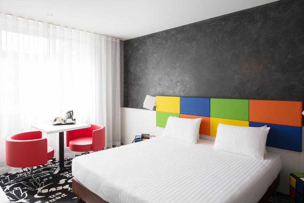 a bedroom with a white bed and a colorful wall at Hotel Tristar in La Louvière