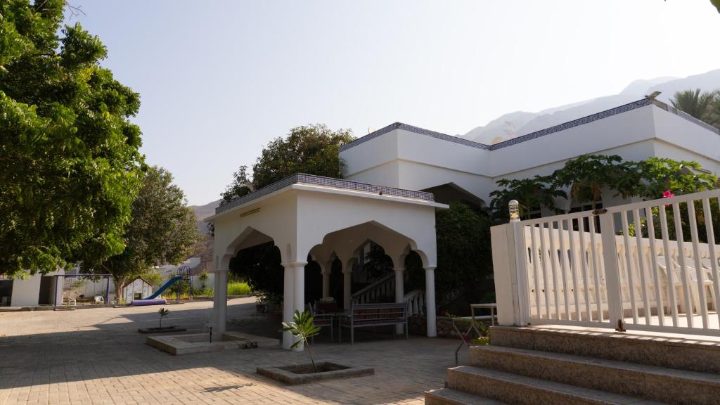 a white house with a white fence and stairs at بيت الشّاب in Ţīwī