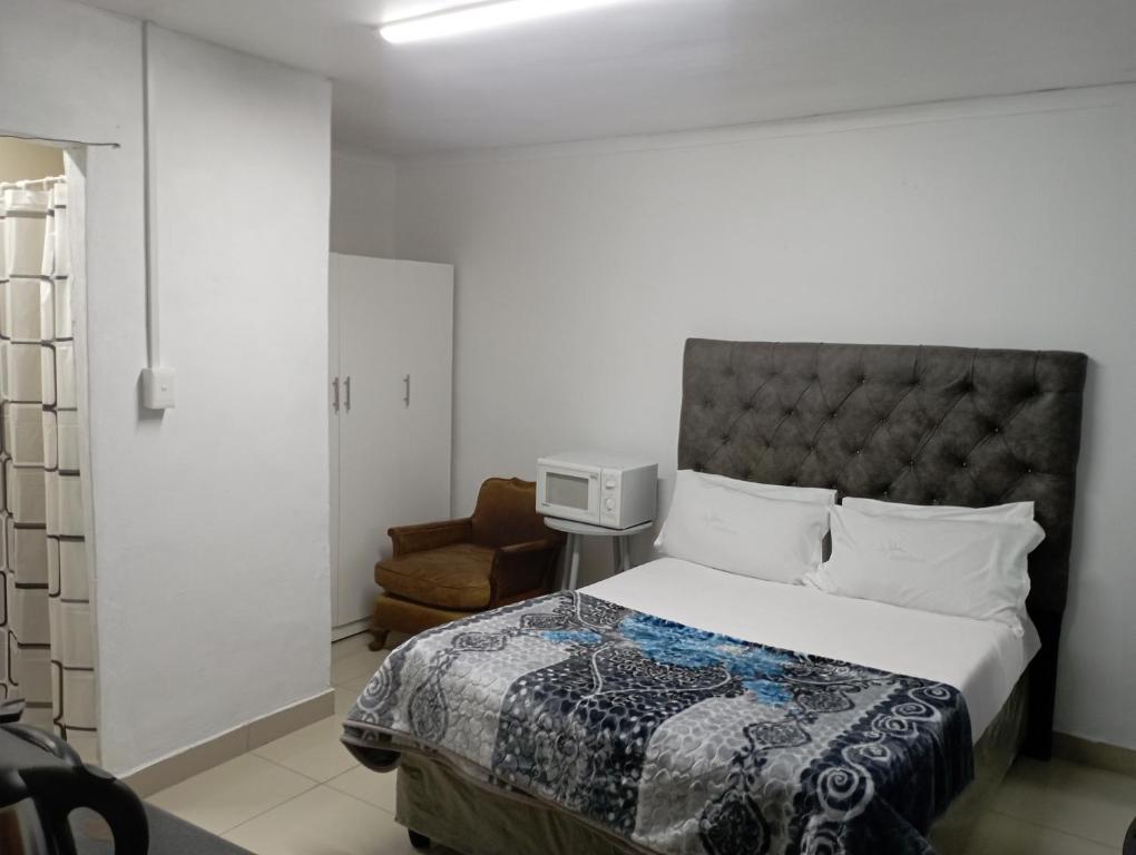 een slaapkamer met een bed en een stoel bij The trout Lodge in Kaapstad