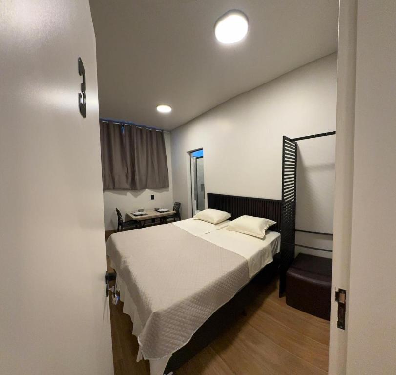 a bedroom with a large bed with white sheets at 3Kitnet nova ao lado de tudo que você precisa in Lavras