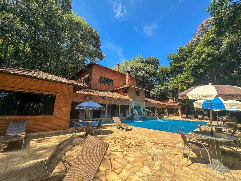 a house with a swimming pool with chairs and umbrellas at Hotel Fazenda Campo dos Sonhos in Socorro
