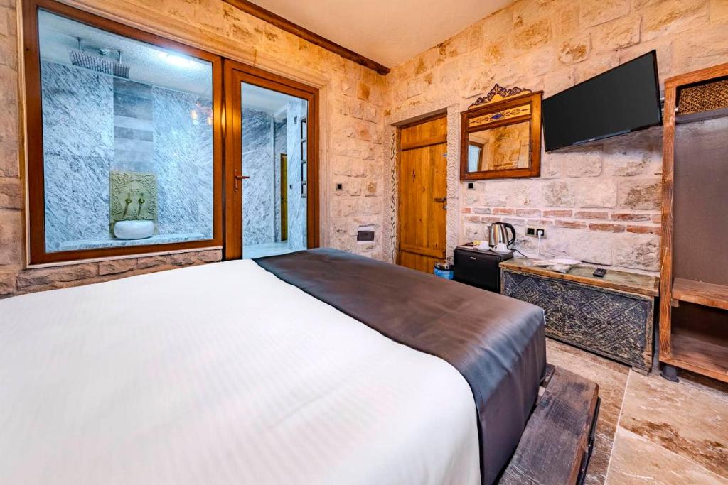 a bedroom with a large bed and a tv at Tuna Guest House in Göreme