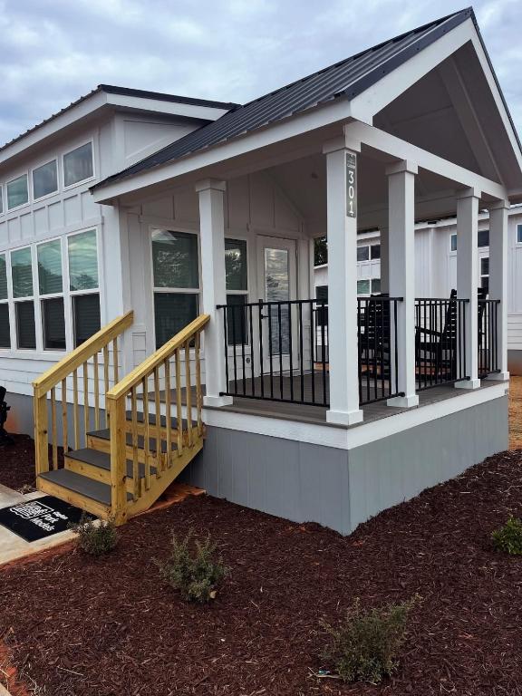 a small white house with a porch and stairs at Carolina Camp Cedar in Pickens