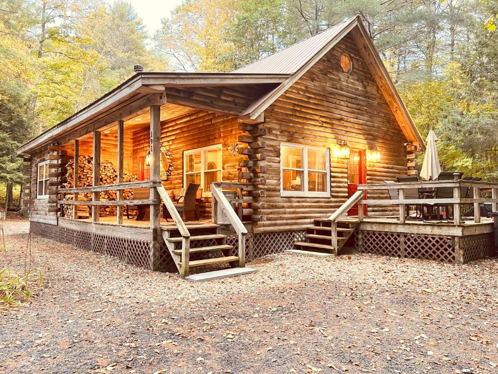 Stylish Forest Lodge with Large Hot Tub, Firepit and Fireplace minutes to Gore Mountain في North Creek: كابينة خشبية مع شرفة وسطح