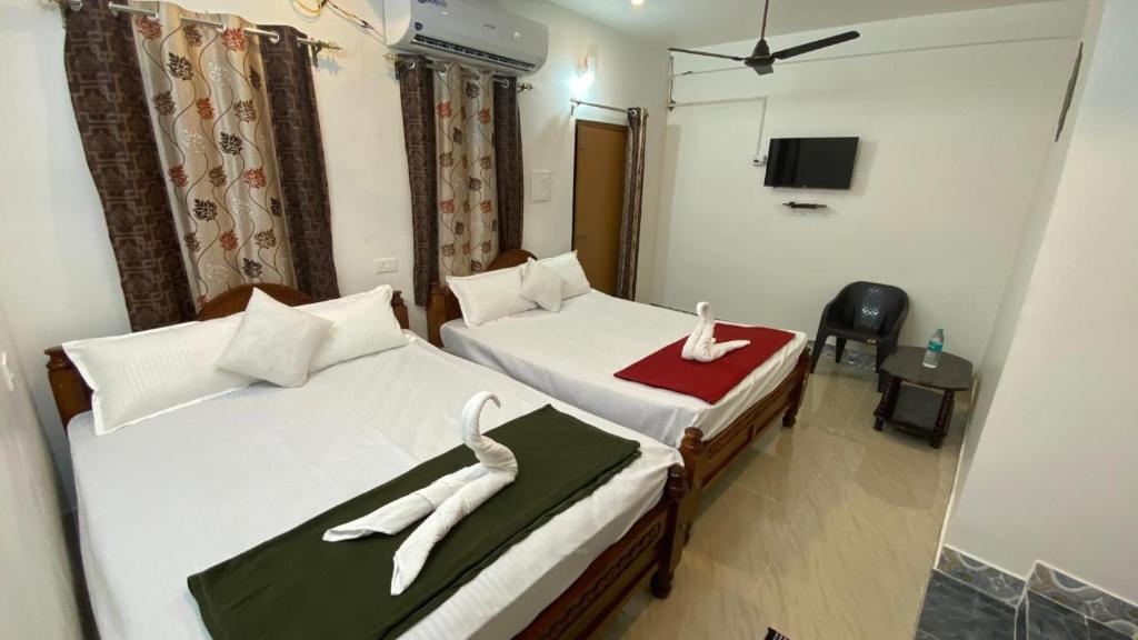 a hotel room with two beds with swans on them at kavieya residency in Pūrnānkuppam