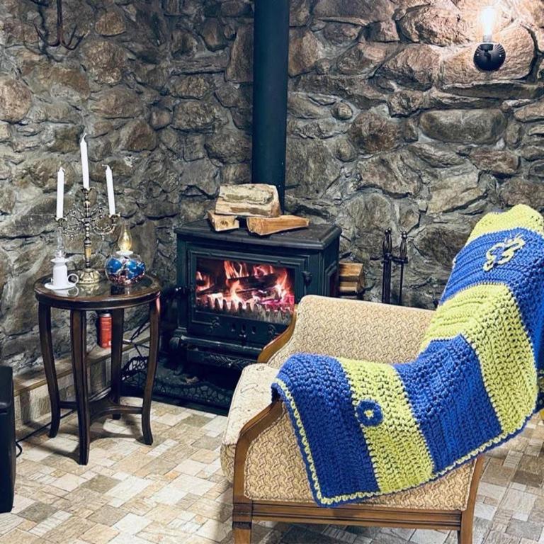 a living room with a fireplace and a chair with a blanket at guesthouse twins in svaneti in Mestia