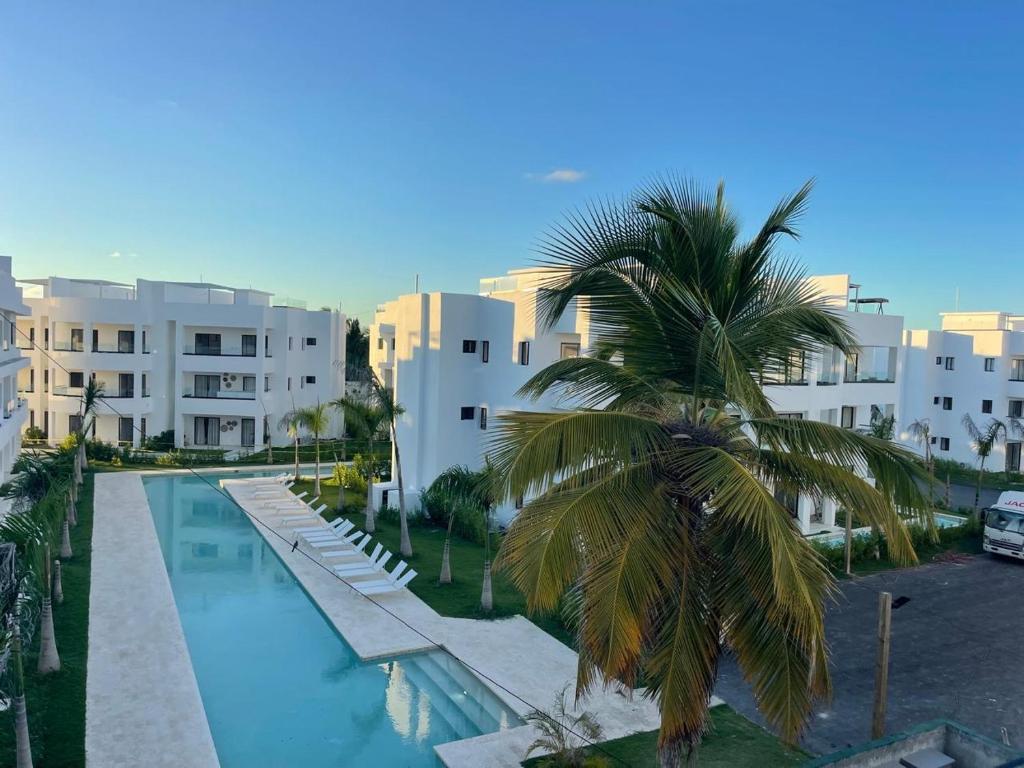 a palm tree in front of a building with a swimming pool at Apartment Luxury ONA Residence, Punta Cana in Punta Cana