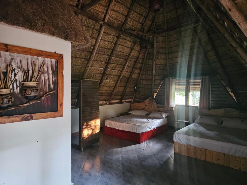a bedroom with two beds in a thatched room at Nguru Farm Cottages in Kabale