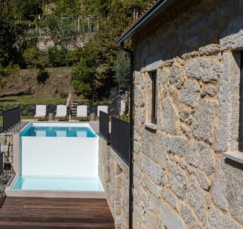 a pool in a stone wall next to a house at Casa das Costinhas in Loureda