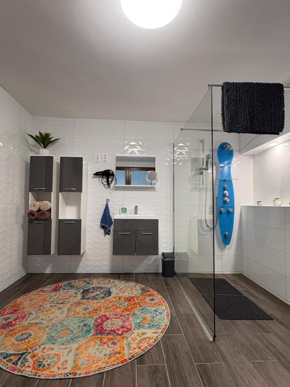 une salle de bain avec une douche et un tapis au sol dans l'établissement Sárffy Vendégház, à Szőce