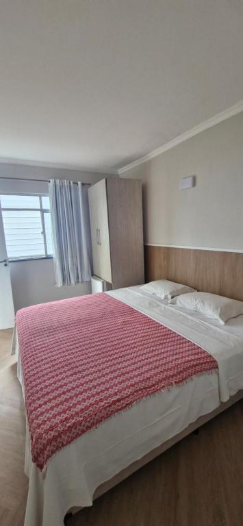 a bedroom with a large bed with a red blanket at Ecopousada Miriti in Belém