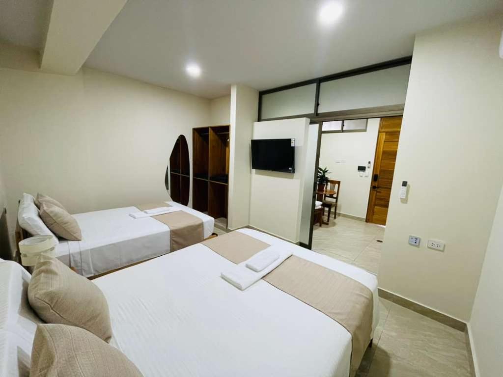 a hotel room with two beds and a flat screen tv at studio confort in Iquitos