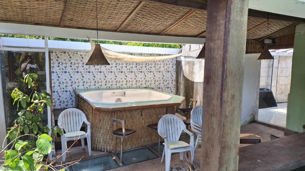 a outdoor kitchen with a bath tub and chairs at Ótima casa próxima a praia e o centro in Ilhabela