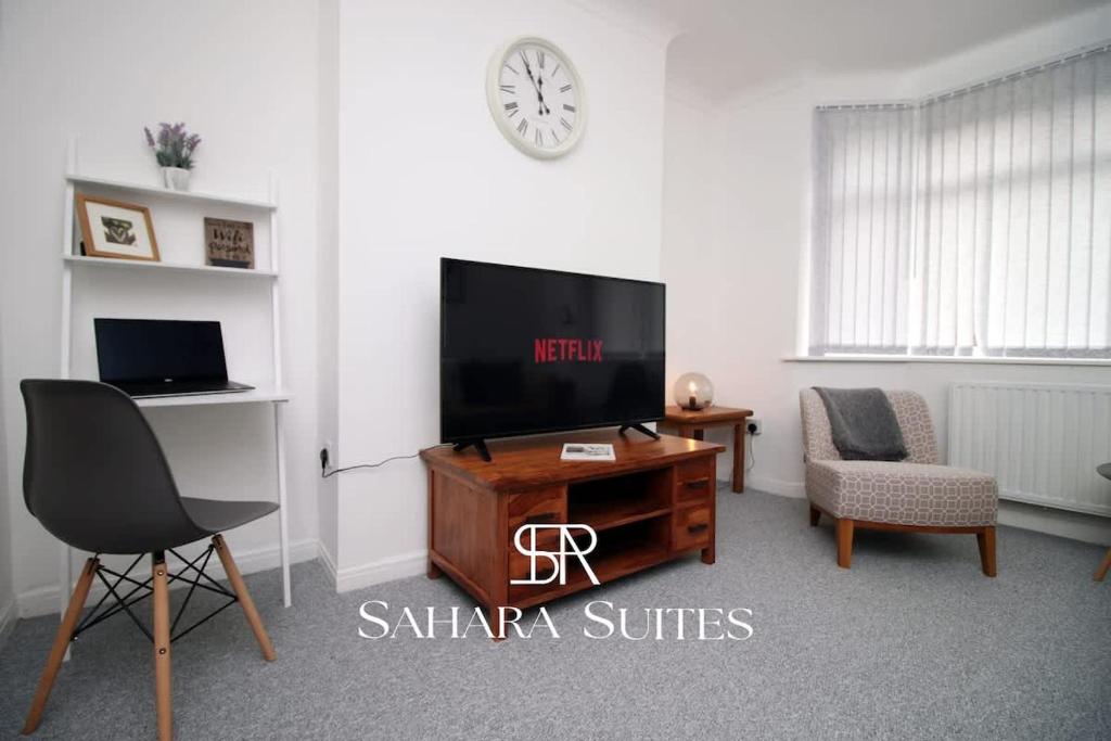 ein Wohnzimmer mit einem TV, einem Tisch und einem Stuhl in der Unterkunft 3BR Retreat Near Tredegar & Newport Hub in Rogerstone