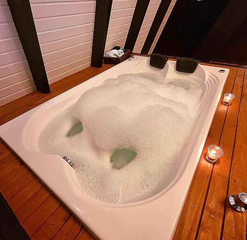 een wit bad bovenop een houten vloer bij Cabana Álamo-Guimarães Reserva in Cambará