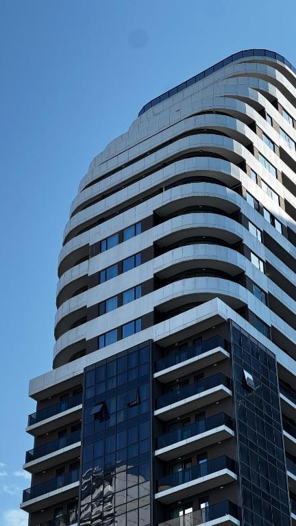 巴统Nova Concierge Aparthotel的一栋高大的玻璃建筑，背景是蓝天