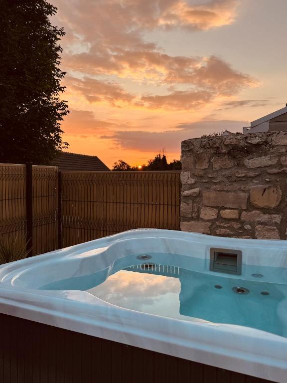 a hot tub in a backyard with a sunset in the background at Chantilly Spa Lodge near Parc Asterix in Montataire