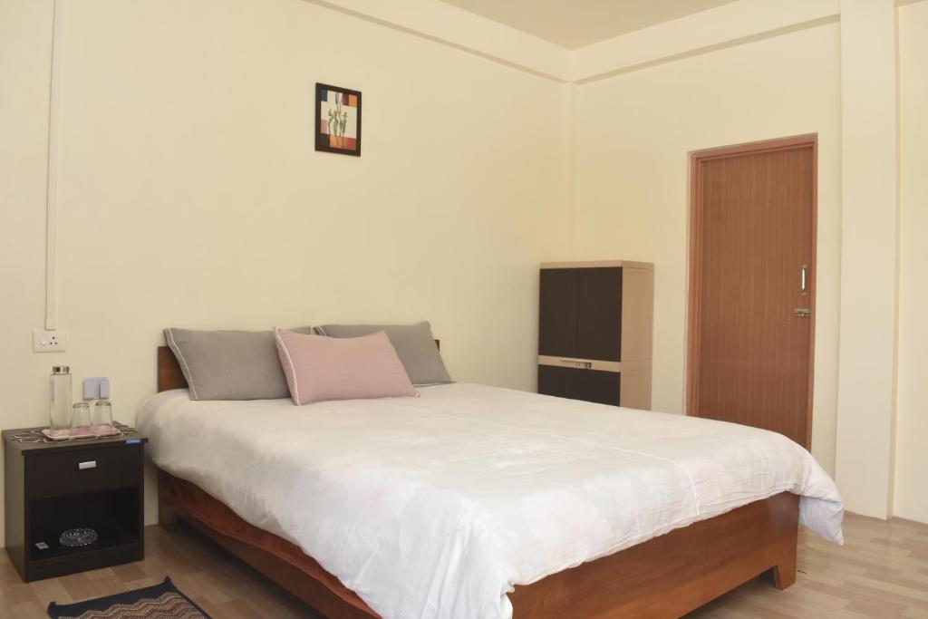 a bedroom with a large white bed and a door at Adoreen Homestay in Cherrapunji
