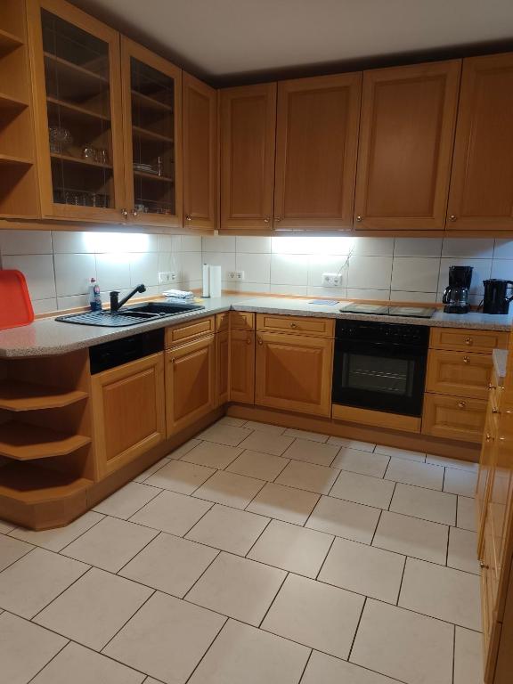 a kitchen with wooden cabinets and a tile floor at Gästehaus Atrico Haus106 in Neubörger
