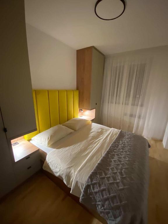 a bedroom with a large bed with a yellow headboard at Diva apartman in Donje Mladice