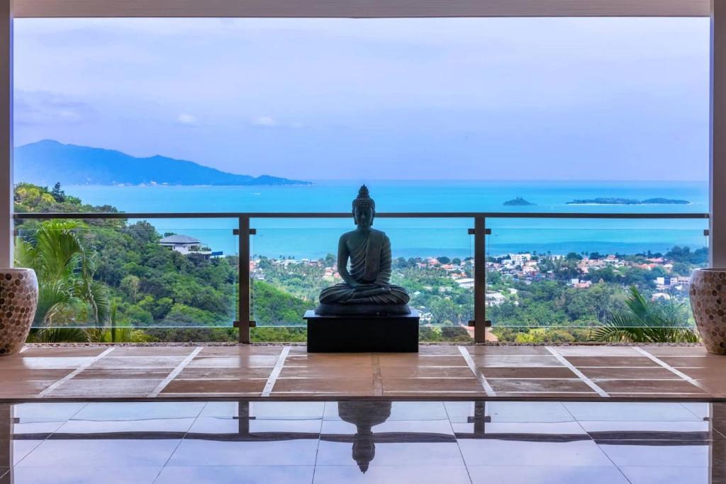 Eine Statue, die auf einem Balkon mit Aussicht thront. in der Unterkunft Here and Now Luxurious Sea view & Spa Villa in Koh Samui 