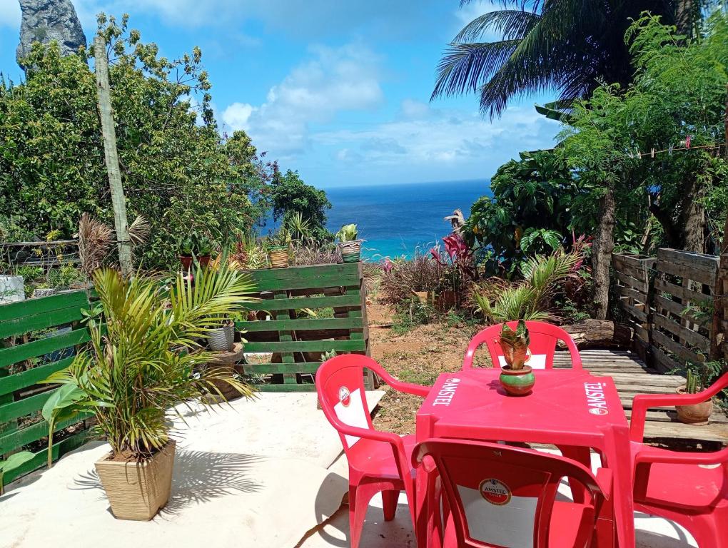 een rode tafel en stoelen met de oceaan op de achtergrond bij Flat sol de Noronha in Fernando de Noronha