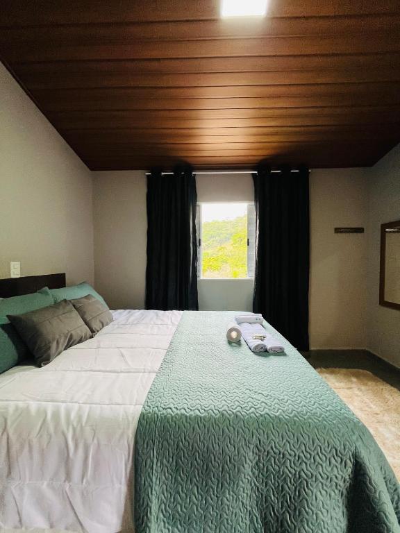 a bedroom with a large bed with a green and white blanket at Estalagem Bernardinos in Camanducaia