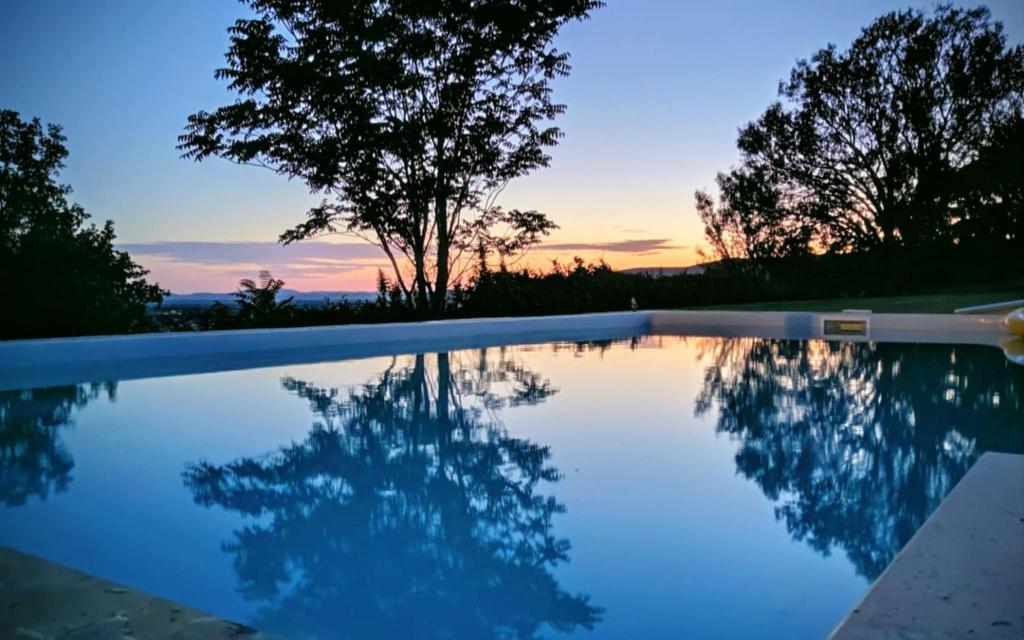 a swimming pool with a sunset in the background at Le Hameau des Lavandes in Roynac