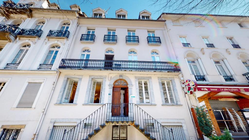 a white building with a red door and balconies at Les Meublés d'Etigny in Luchon