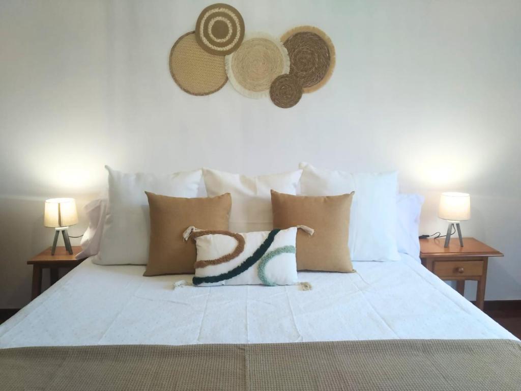 a white bed with pillows and hats on the wall at Apartamento Ziralla- con Garaje Gratis in Allariz