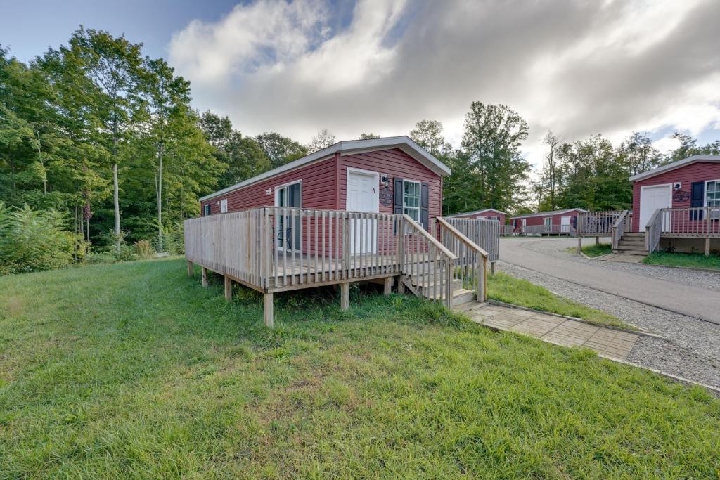 a red cabin with a porch and a wooden deck at Cassopolis Cabin with On-Site Fishing Pier! in Cassopolis