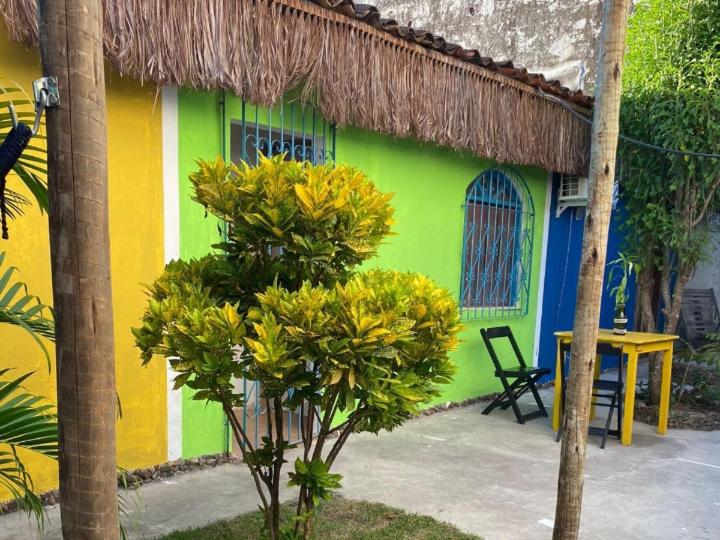 a green and yellow house with a table and chairs at Hostel Itaparica in Itaparica Town