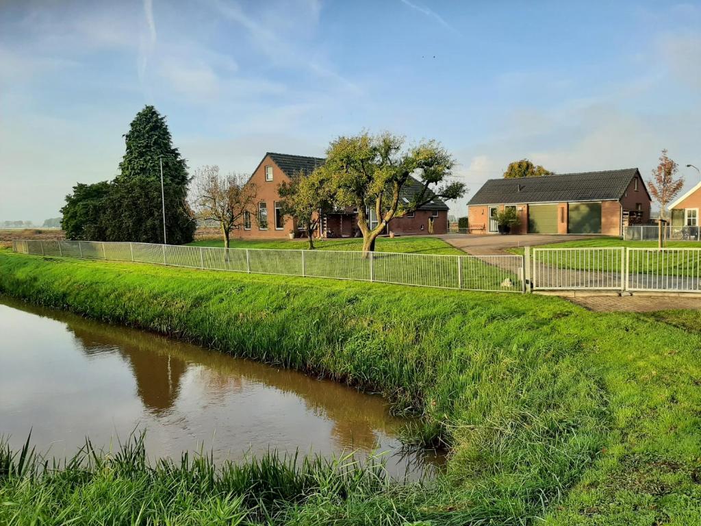 a river with a fence next to a house at het Veenhuus in Nieuwlande
